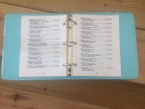 Small light blue three-ring binder opened showing two-pages of names, addresses and TTY phone numbers.